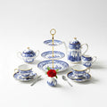 Elegant blue and white china tea set with gold accents displayed on a white surface with a rose